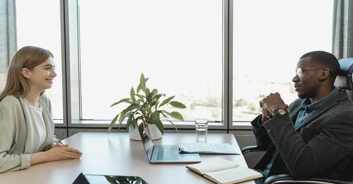 Entretien d'embauche engageant entre deux collègues dans un bureau moderne et lumineux.