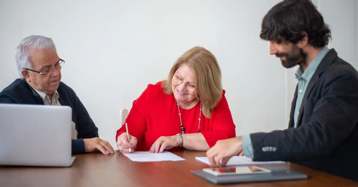 Des professionnels d'affaires seniors signant des documents lors d'une réunion dans un bureau lumineux.