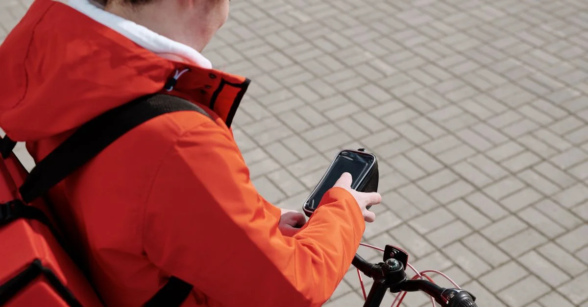 Livreur à vélo consultant son smartphone pour des directions.