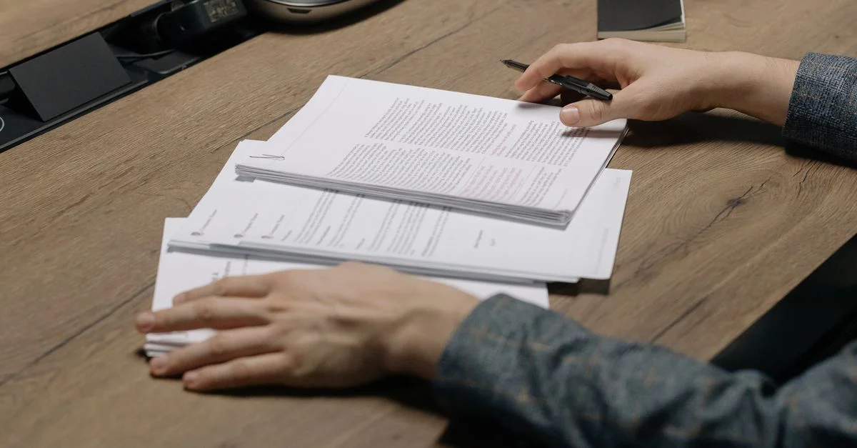 Gros plan sur une personne consultant des documents avec un stylo à un bureau moderne.