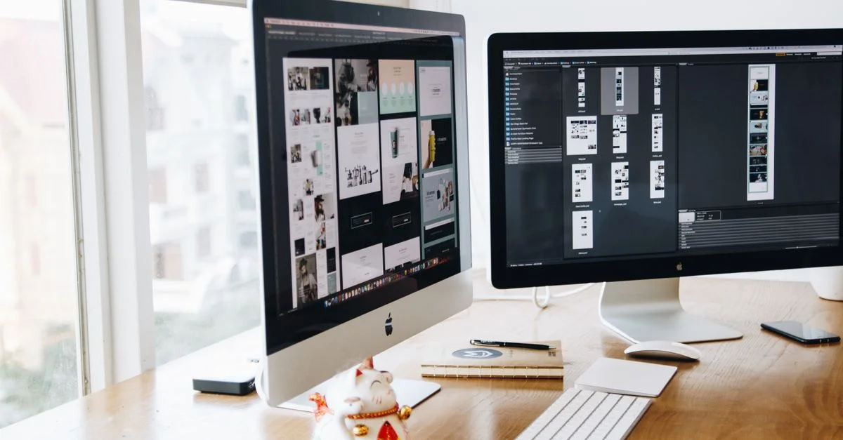 Un bureau moderne élégant avec des écrans doubles, des appareils Apple et une décoration créative dans un espace de travail intérieur.