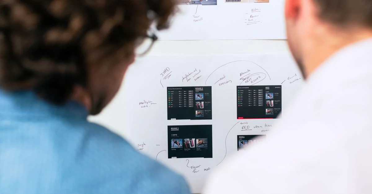 Deux professionnels discutent et planifient le développement de logiciels avec un tableau blanc dans un bureau.