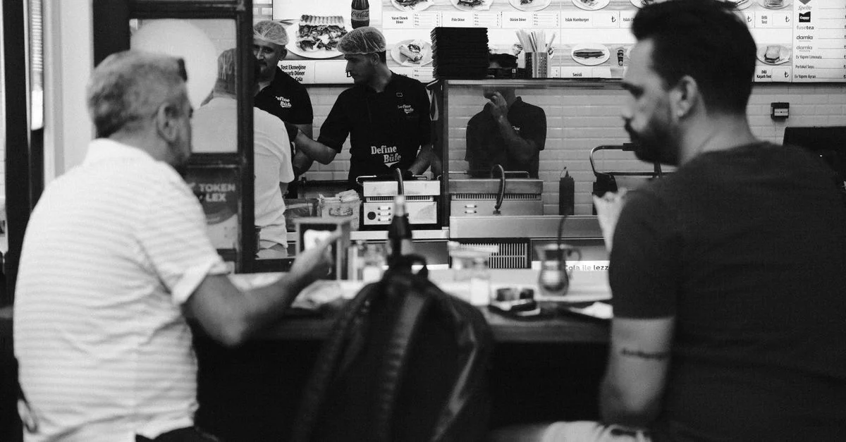 Photo monochrome d'un fast-food avec des clients et du personnel derrière le comptoir.