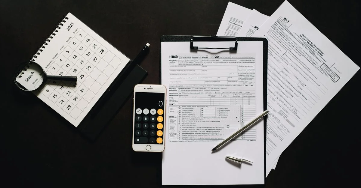 Vue de dessus des outils financiers pour la préparation des impôts, y compris des formulaires, une calculatrice et un calendrier.