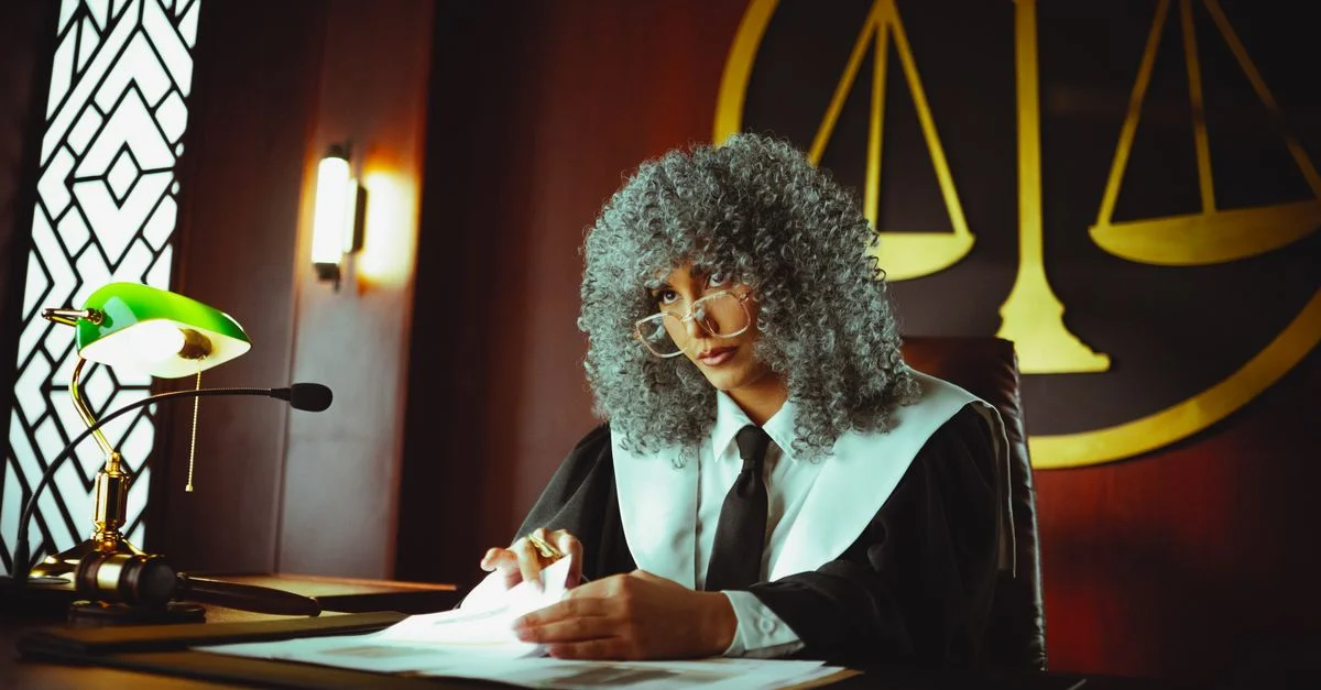 Un juge dans un tribunal examinant des documents sous une lampe verte classique.