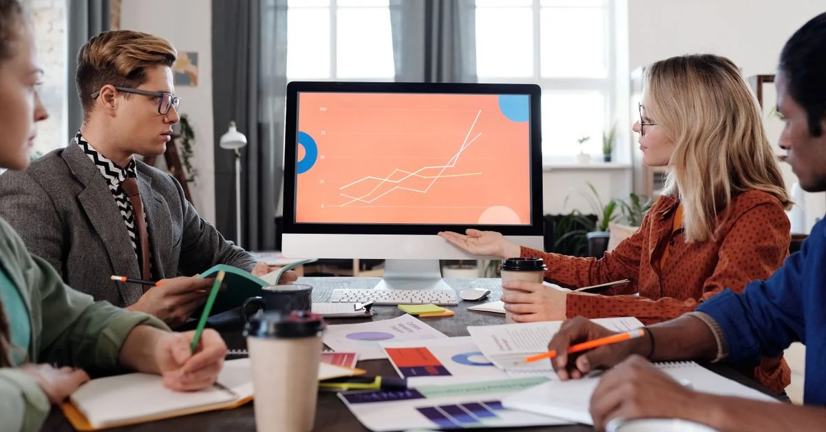 Une équipe diversifiée discute de la visualisation des données sur un écran d'ordinateur dans un environnement de bureau.
