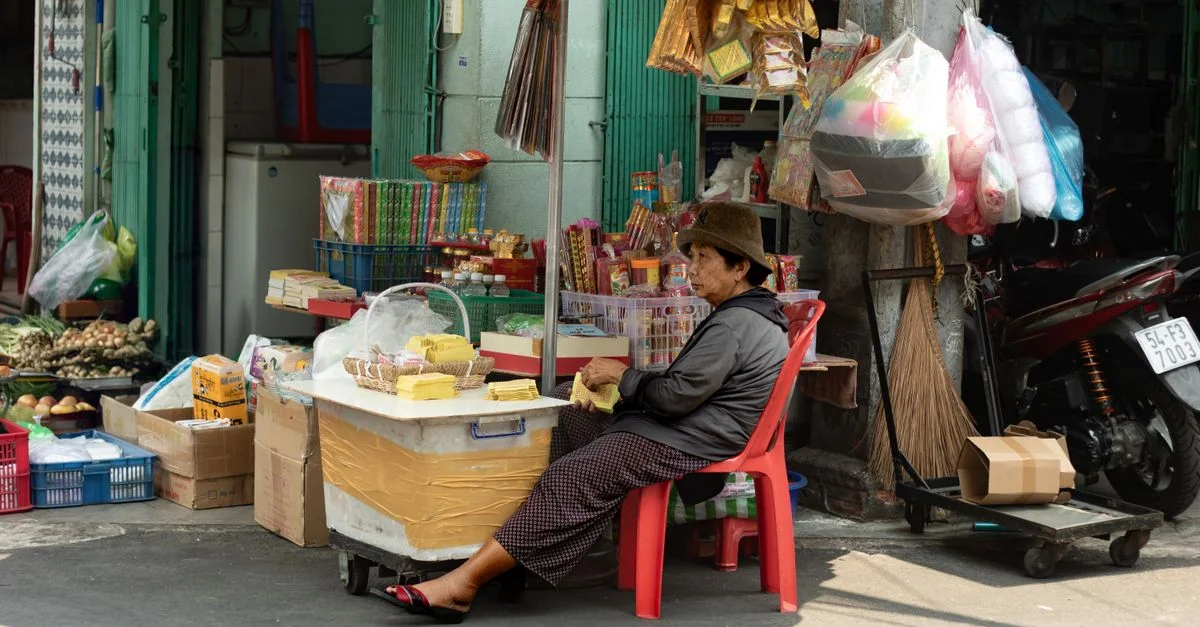 Vendeur de rue à Ho Chi Minh-Ville vendant des marchandises avec en toile de fond l'atmosphère du marché local.