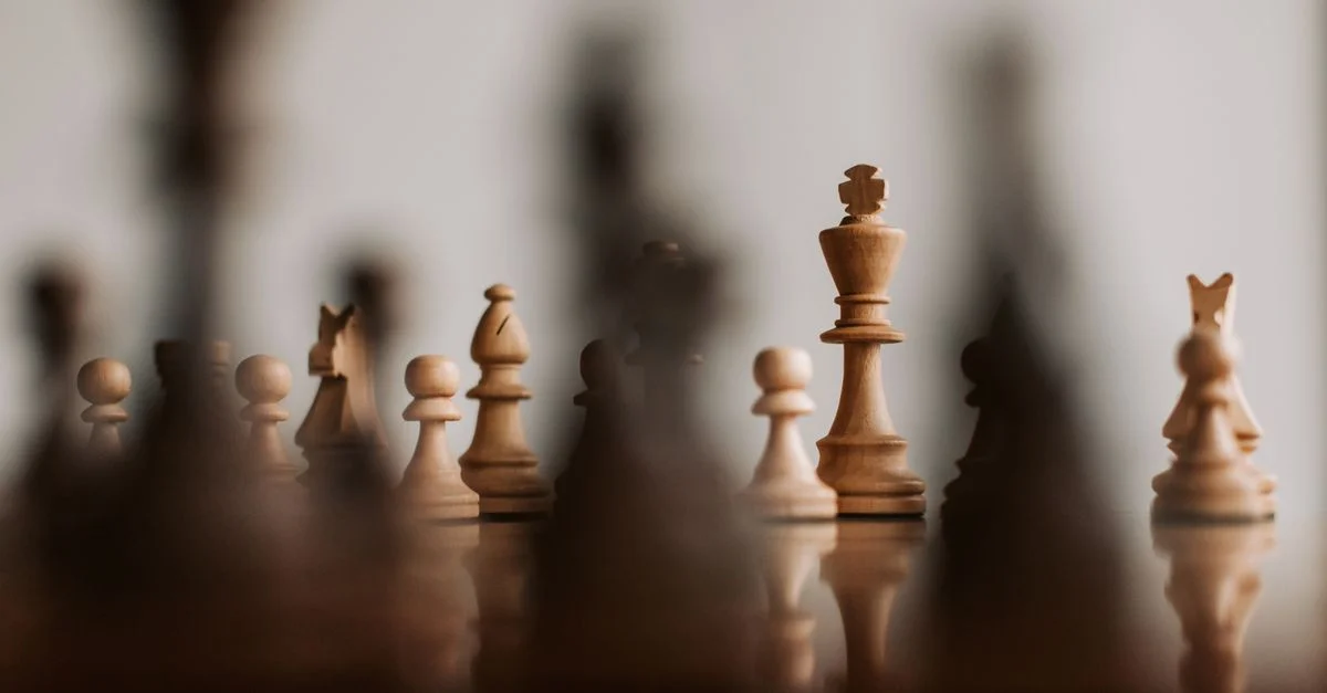 Vue en gros plan d'un échiquier avec des pièces en bois, mettant l'accent sur le roi, montrant la stratégie et la profondeur de champ.