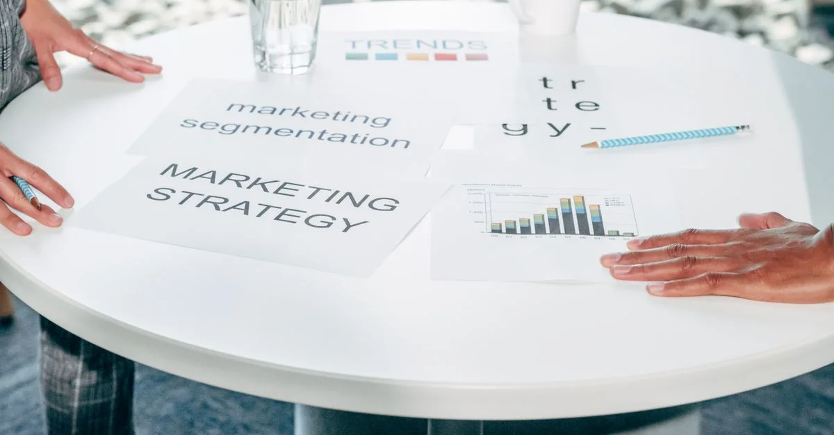 Deux professionnels collaborent sur la stratégie marketing et la segmentation autour d'une table ronde.