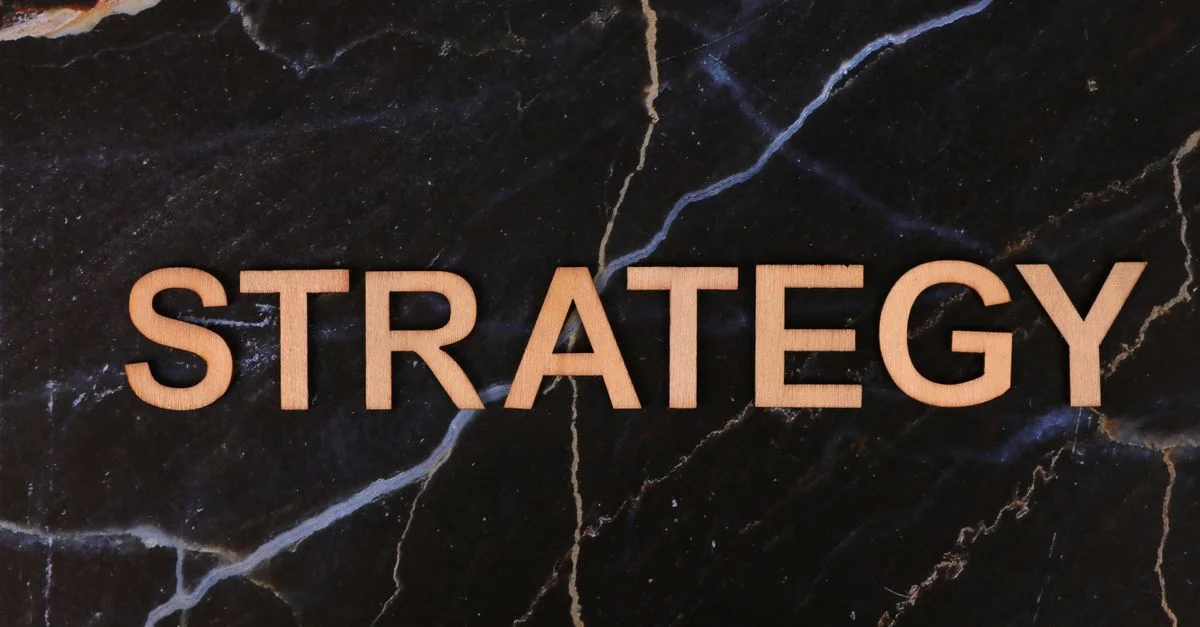 Concept de planification stratégique avec le mot « Stratégie » en lettres de bois sur du marbre foncé.