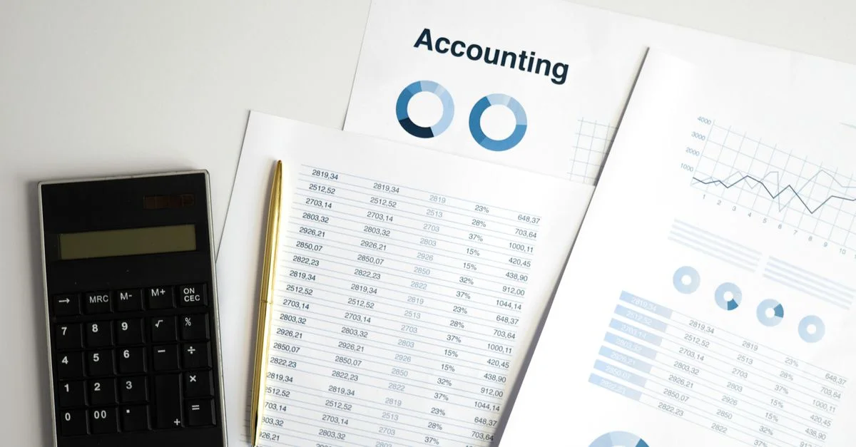Calculatrice et documents comptables avec graphiques sur un espace de travail.