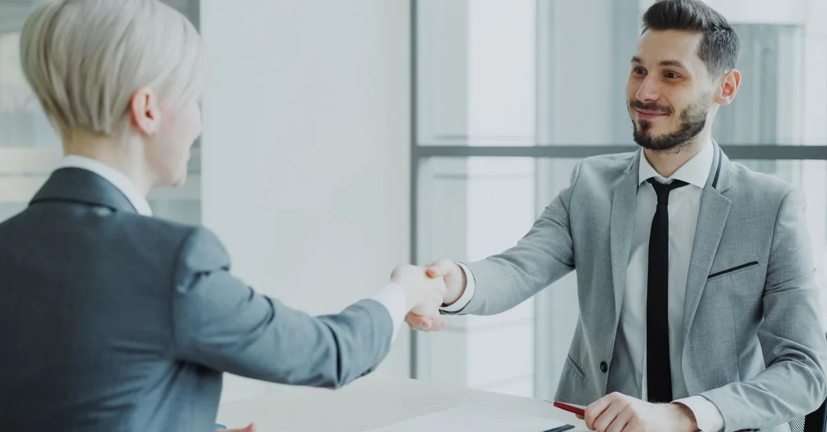Deux professionnels se serrant la main dans un environnement de bureau moderne et lumineux.