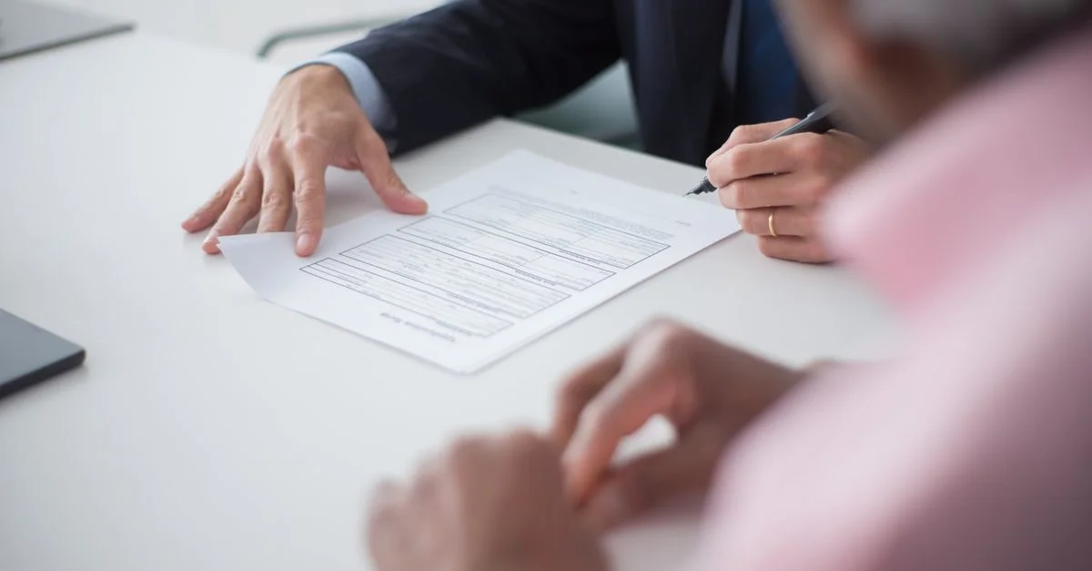 Deux professionnels participant à une réunion d'affaires, signant des documents pour un accord de consultation.