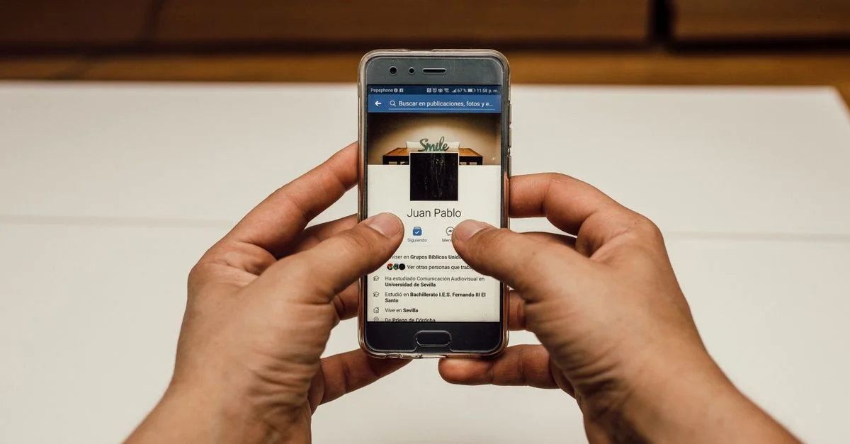 Gros plan sur des mains utilisant un smartphone avec une page de médias sociaux à l'intérieur.