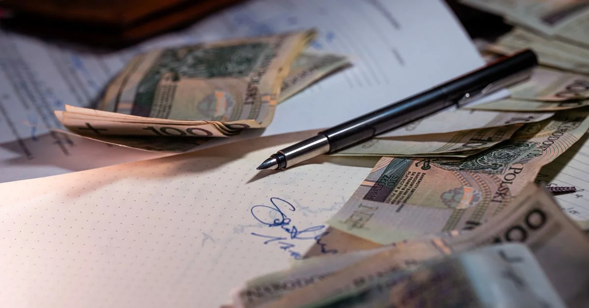 Vue de dessus de billets polonais, de documents et d'un stylo sur un bureau, mettant en avant la planification financière.
