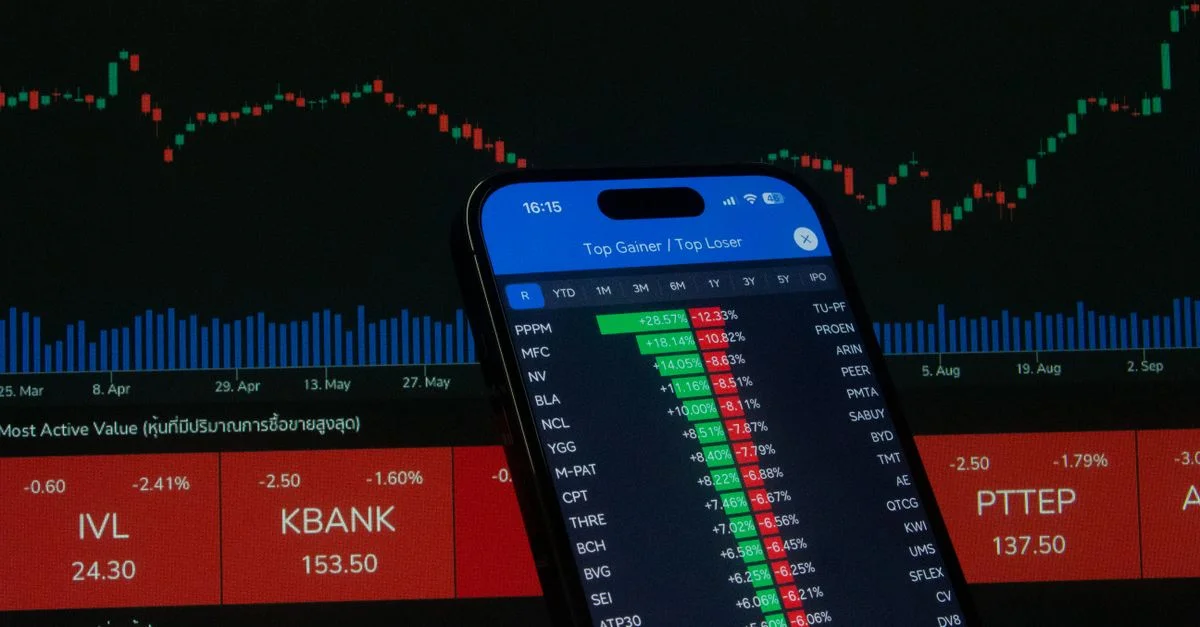 Smartphone avec des données boursières devant un graphique financier.